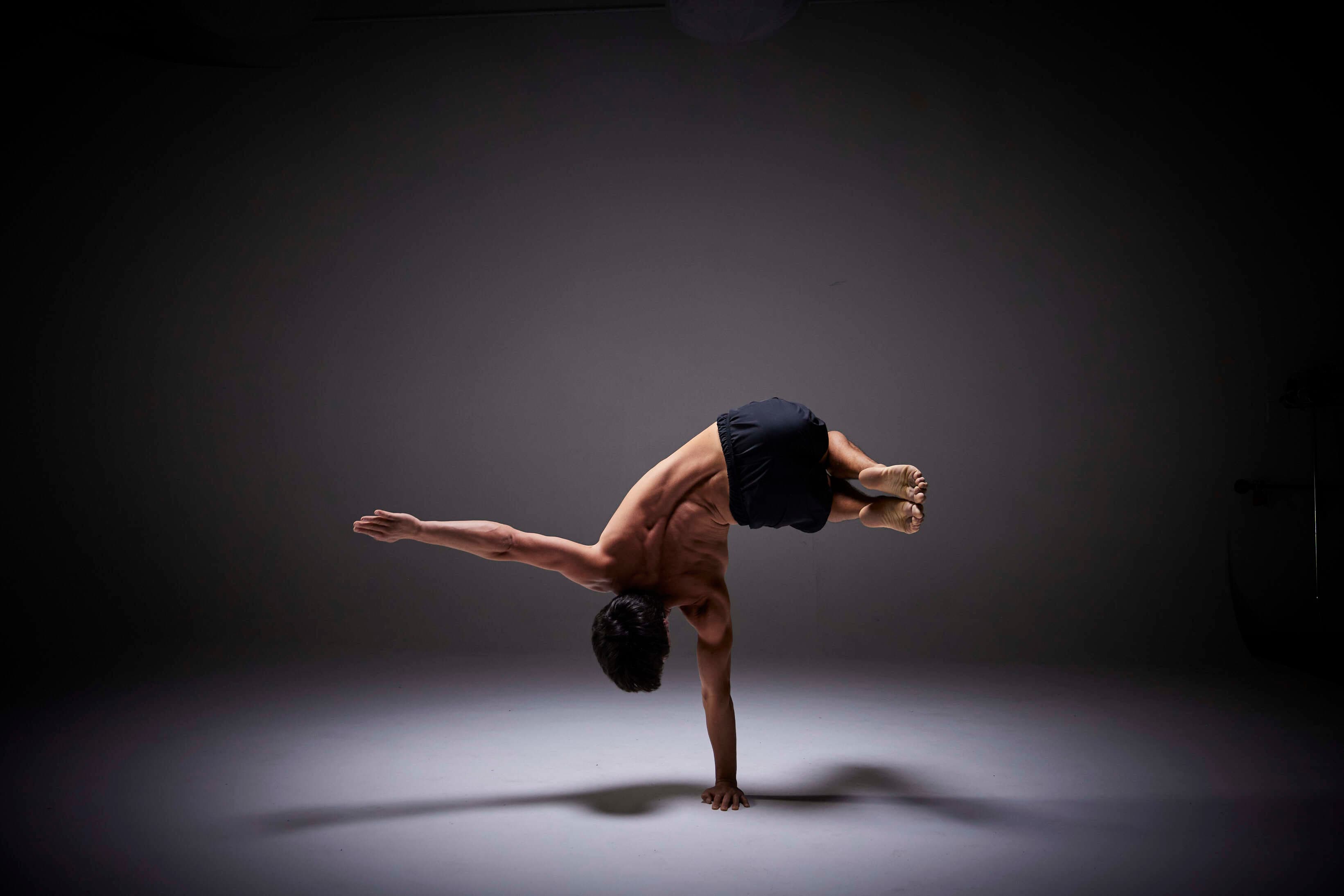 Josh Lee balancing on one arm, legs tucked