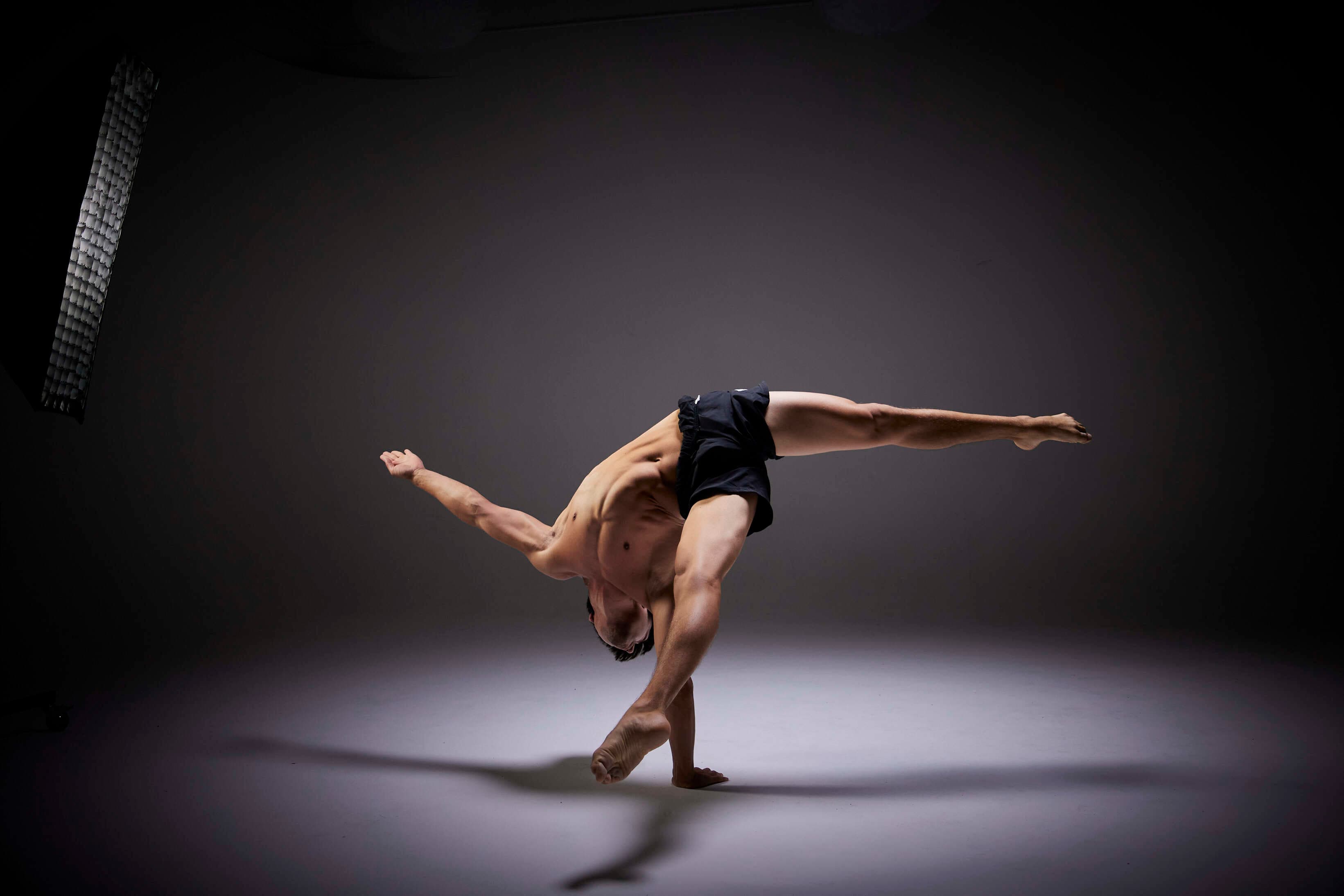 Josh Lee balancing on one arm, legs wide