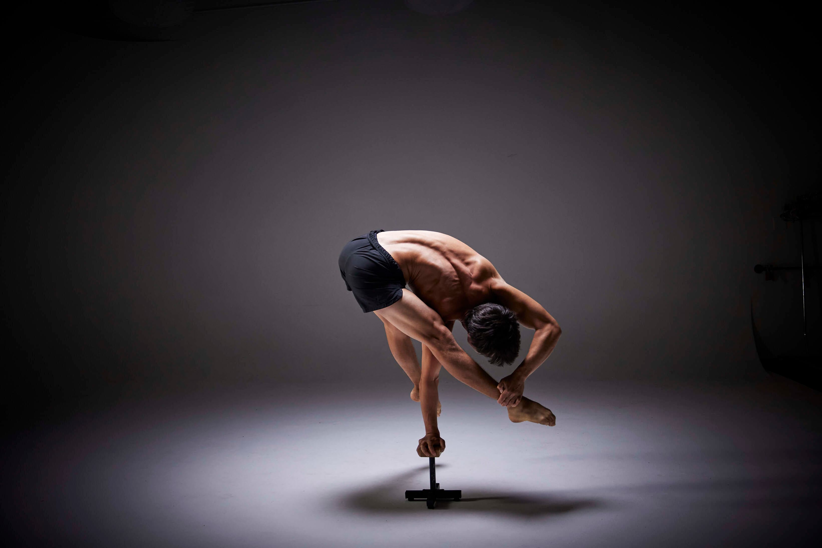Josh Lee folded over one arm on a handstand cane