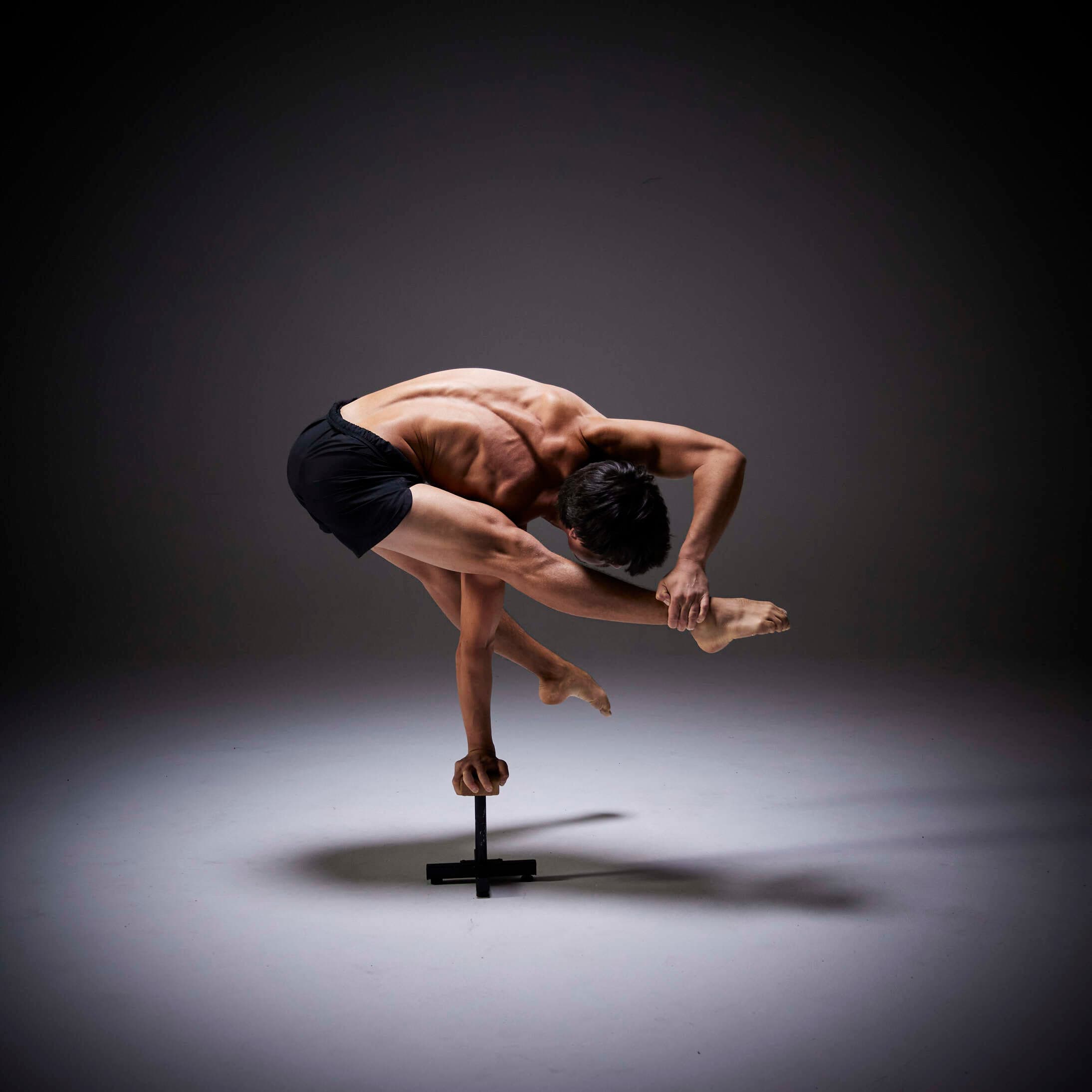 Josh Lee folded over one arm on a handstand cane